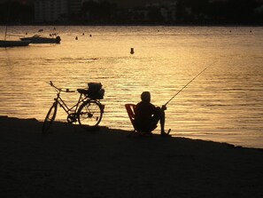 A silhouette of a person fishing by the water with a bicycle parked nearby. - Old Town -  Palma La Lonja (Palma)
