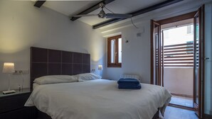 Ein Schlafzimmer mit einem großen Bett, einem Nachttisch mit Lampe und einem Fenster mit Jalousien.