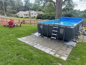 En baghave med swimmingpool, træterrasse og en rød stol.