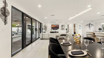 A modern dining area with a long table, chairs, and a view of the outdoors.