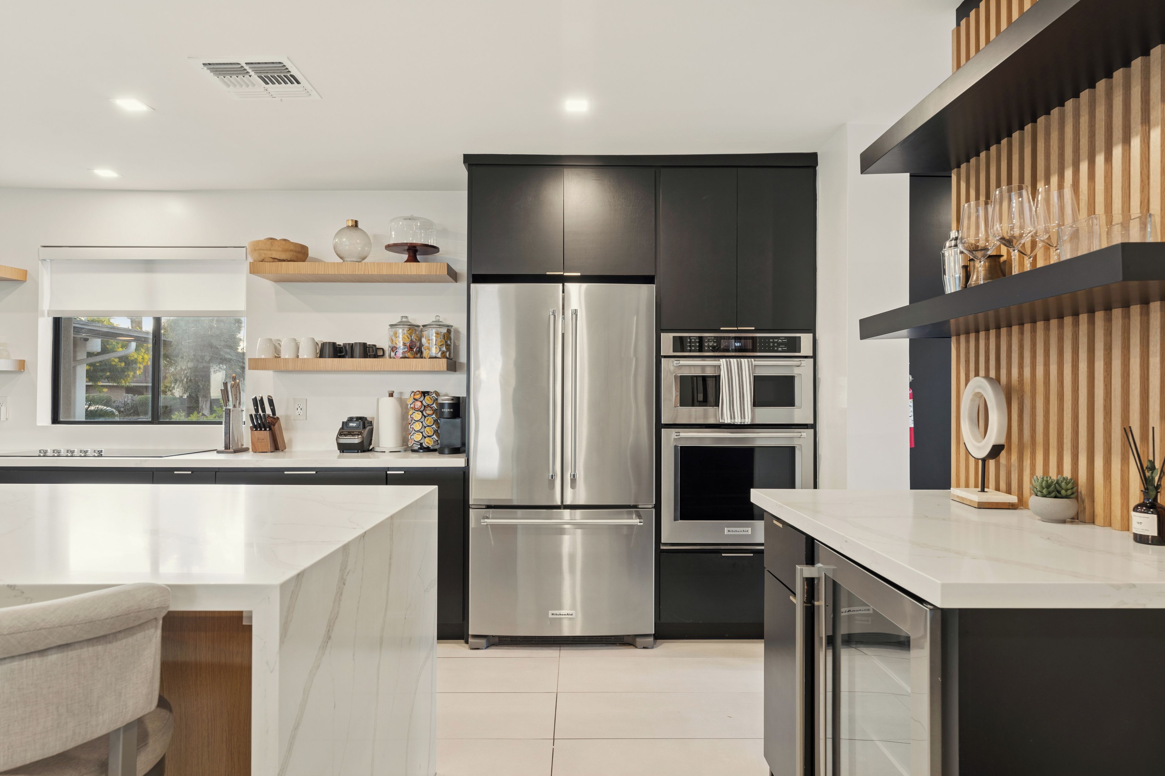 A modern kitchen with a stainless steel refrigerator, built-in oven, and microwave.