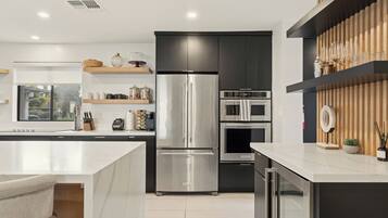 A modern kitchen with a stainless steel refrigerator, built-in oven, and microwave.