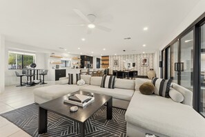 A modern living room with a sectional sofa, a coffee table, and a dining area in the background. - Villa Makena: Huge Luxe Home | Pickleball Court | Heated Pool | Great for Groups (Scottsdale)
