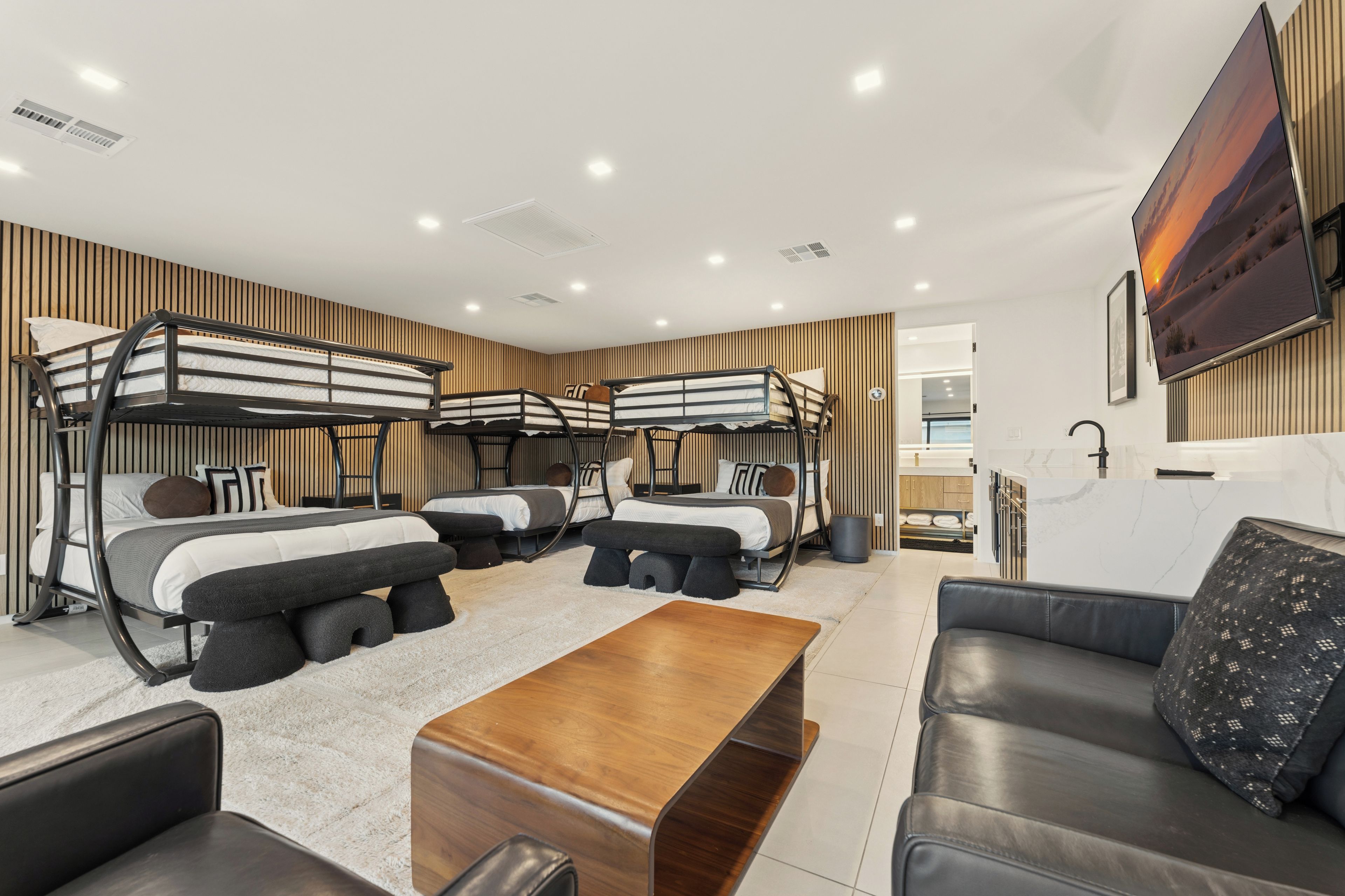 Bunk room with three bunk beds, a TV and a leather sofa.