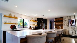 Een moderne keuken met een centraal eiland, barkrukken en inbouwplanken.