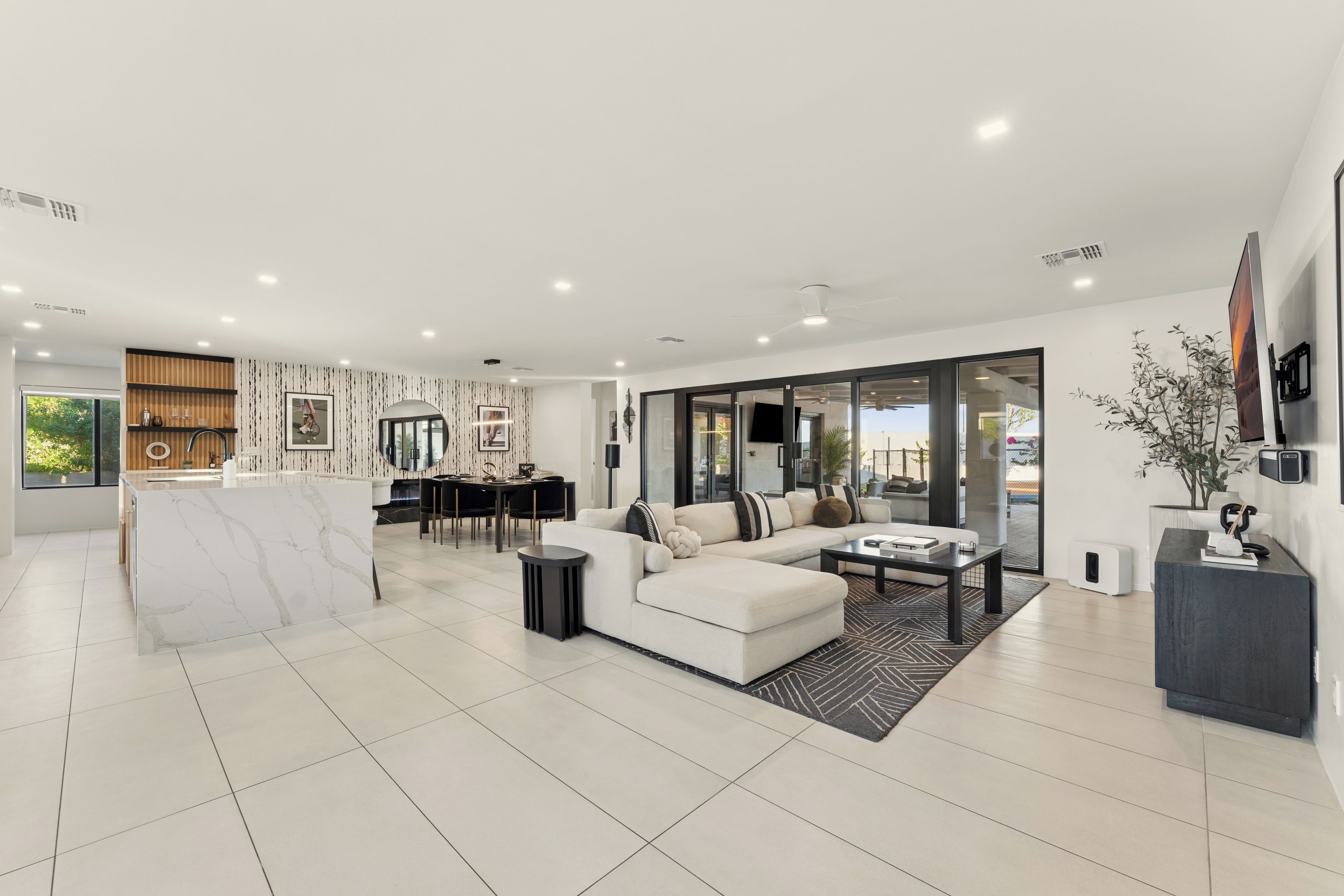 A modern living room with a sofa, coffee table, and a dining area with a table and chairs.