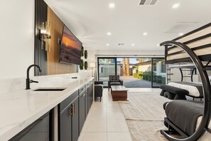 A modern kitchen with a large island, a dining area with a sofa and table, and a view of the outdoors.