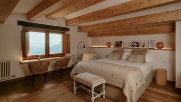 Ein Schlafzimmer mit einem großen Bett, einem Schreibtisch mit Stühlen, einem Fenster und Holzbalken an der Decke.