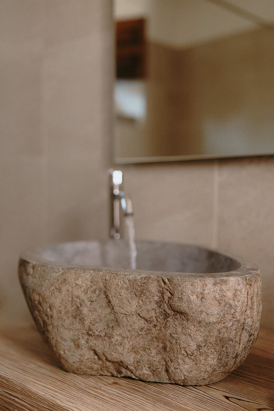 Un lavabo de piedra con un grifo moderno sobre una encimera de madera.