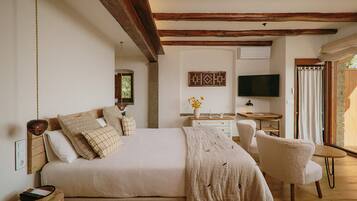 Un dormitorio con una cama grande, un escritorio, una silla, un televisor y una ventana con cortinas.
