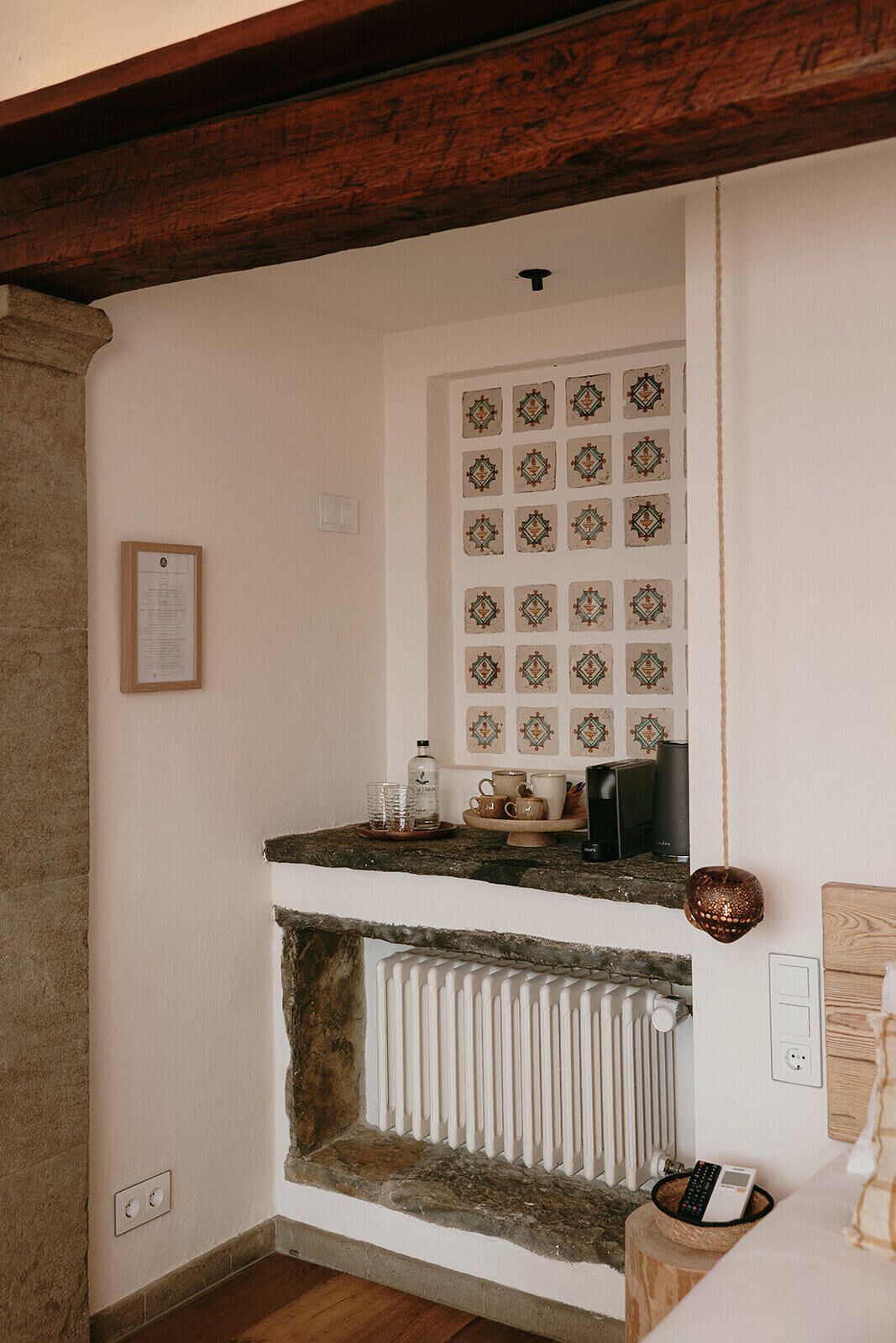 Una cocina con chimenea de piedra, salpicadero de azulejos y viga de techo de madera.