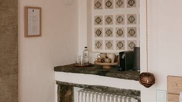 Una cocina con chimenea de piedra, salpicadero de azulejos y viga de techo de madera.