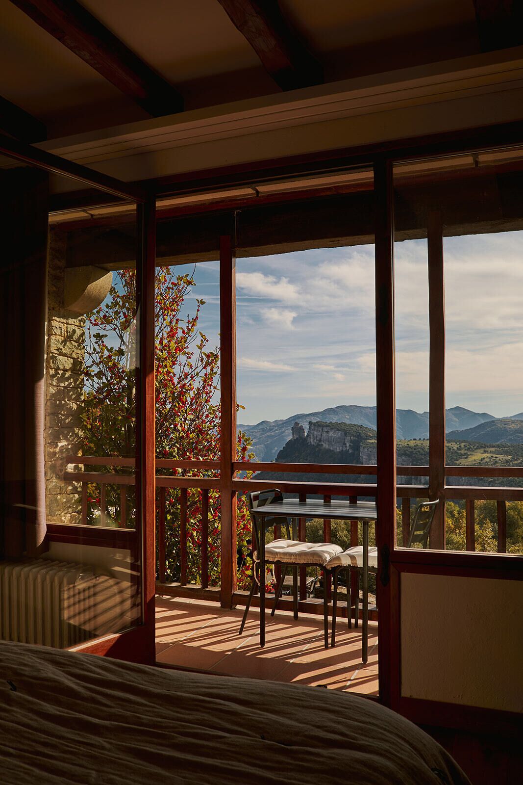 Une pièce avec une grande fenêtre, un lit, une table et des chaises.