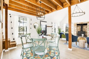 Un vaste espace de vie comprenant une table à manger, des chaises, une cheminée et un escalier.