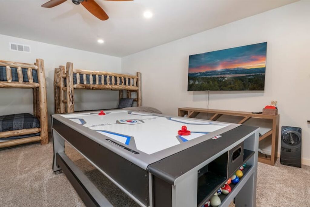 A room with a pool table, bunk beds, a painting, and a trash can.