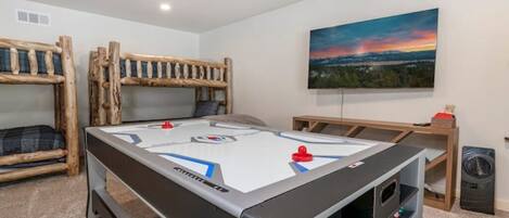 A room with a pool table, bunk beds, a painting, and a trash can.