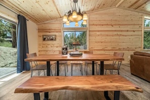A wooden interior with a large dining table, chairs, and a bench.