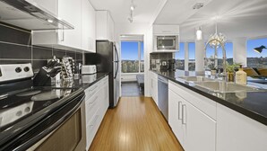 Una cocina moderna con una isla central, electrodomésticos de acero inoxidable y vistas a la ciudad.
