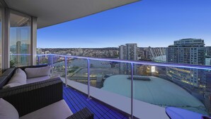 Un balcón con vista a un paisaje urbano, incluyendo un estadio y rascacielos.