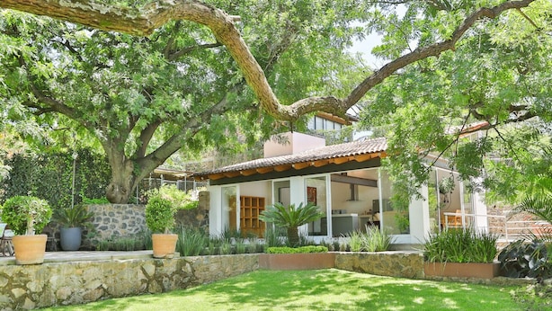 Une maison dotée d’un patio couvert, de murs en pierre et d’une pelouse bien entretenue.