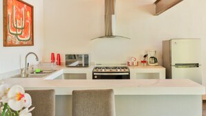 Une cuisine moderne dotée d’un îlot central, d’appareils électroménagers en acier inoxydable et d’un design minimaliste.
