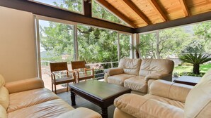 Une terrasse ensoleillée avec des canapés en cuir, une table en bois et une chaise.