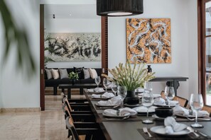 Enjoy a meal at the dining table, surrounded by a beautiful abstract art piece and a comfortable sofa.