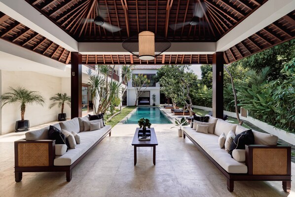 Relax in a serene setting with a central seating area, sofa, and pool views.