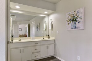 A bathroom with a double sink vanity, a large mirror, and a painting of a vase with flowers on the wall. - AMAZING  3 Bedroom - 3 Bath Condo / Gorgeous Views / Heart of Branson / Spacious (Branson)