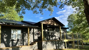Uma casa de dois andares com varanda coberta e área de deck cercada.