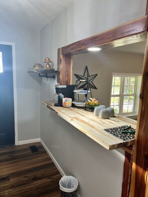 Een keuken met een houten aanrecht, een koffiezetapparaat, een ster decoratie, en een raam met uitzicht op bomen.