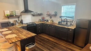 Cozinha moderna com bancada de madeira, eletrodomésticos de aço inoxidável e forno embutido.