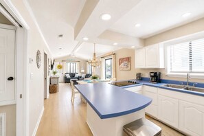 A modern kitchen with a central island, white cabinetry, and a blue countertop.