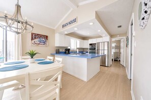 Una cocina moderna con armarios blancos, encimera azul y un refrigerador de acero inoxidable.