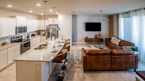 A modern kitchen with white cabinets, stainless steel appliances, and a central island with bar stools.