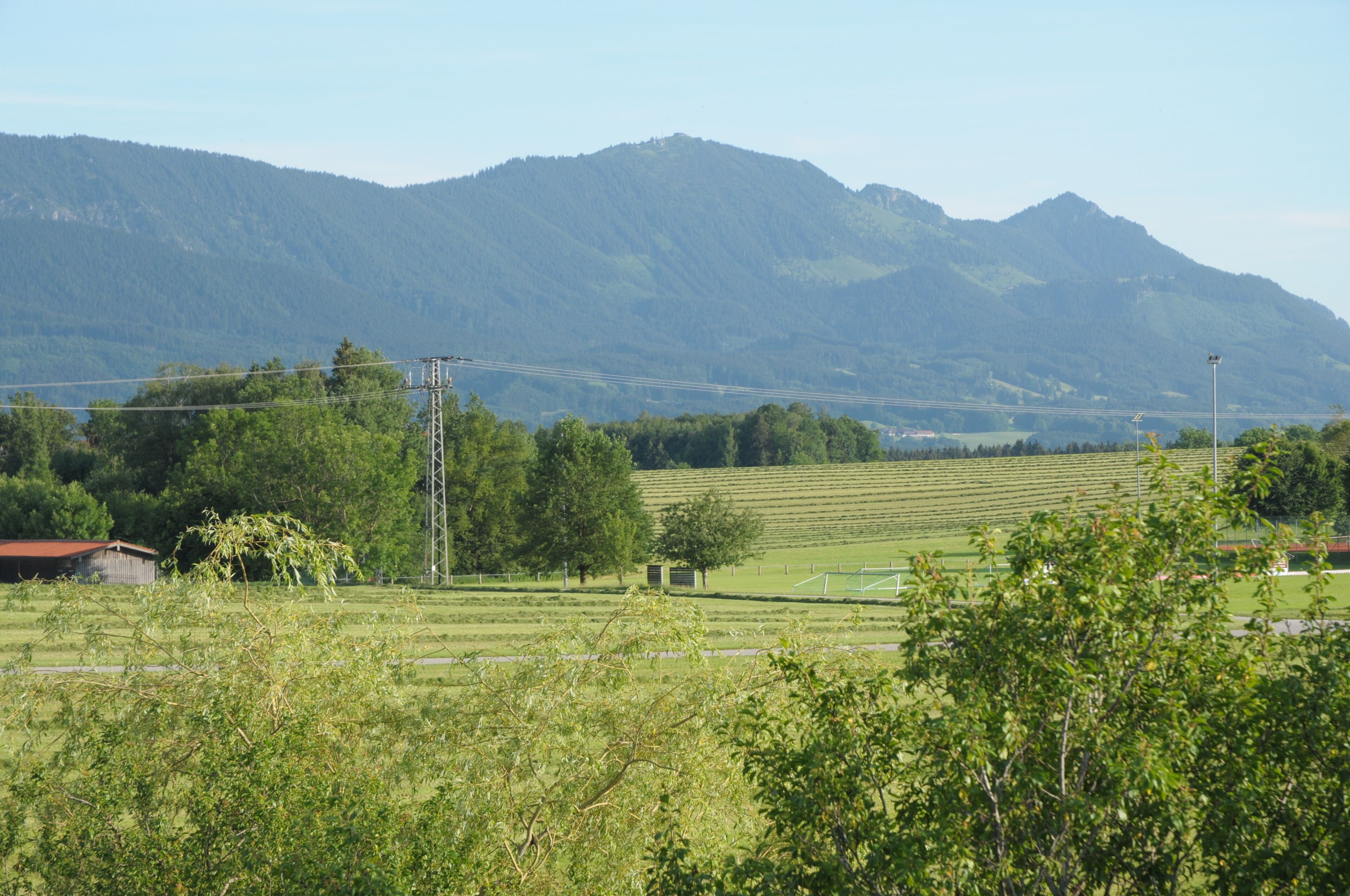 Un paysage rural avec une montagne en arrière-plan, un champ et un petit bâtiment.