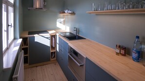 Una cucina compatta con piano di lavoro in legno, elettrodomestici integrati e una finestra che garantisce luce naturale.