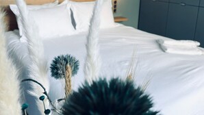 Una cama bien tendida con sábanas blancas, cabecera de madera y lámpara de noche.