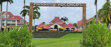 L’entrée d’un complexe hôtelier, avec une enseigne indiquant « Pierre & Vacances », et en arrière-plan, une vue sur les bâtiments du complexe.