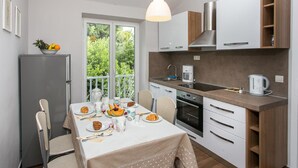 Una cucina moderna con zona pranzo, dotata di frigorifero, macchina del caffè e bollitore sul piano di lavoro.