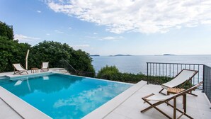 Una piscina con lettini e vista sul mare.