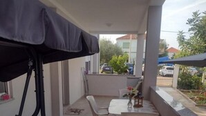 A balcony with a table and chairs, a striped sofa, and a covered area. - Apartments Franica - Three Bedroom Apartment with Terrace (Zadar)