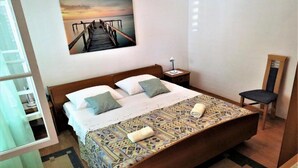 A neatly arranged bedroom with a bed, pillows, a bedside table, a chair, and a wall-mounted picture. - Apartments Franica - Three Bedroom Apartment with Terrace (Zadar)