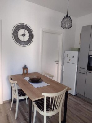 Ein Essbereich mit Holztisch, vier Stühlen, einer Wanduhr und einer Pendelleuchte.