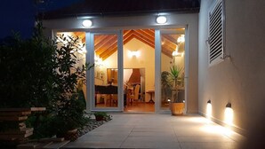 A modern house with a glass door entrance, a wooden deck, and a potted plant.