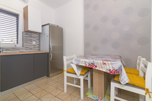 Una cocina compacta equipada con refrigerador, pileta y comedor con mesa y sillas.
