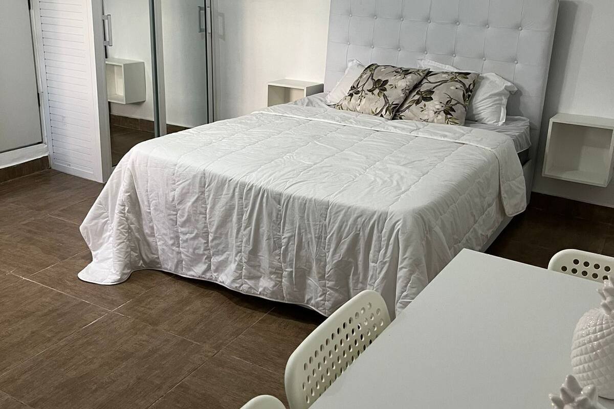 Une chambre à coucher avec un lit, une table blanche et des chaises.