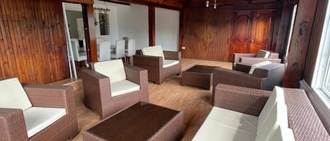 Un espace intérieur vaste et lumineux, aménagé avec des meubles en osier et doté d’un plancher en bois.
