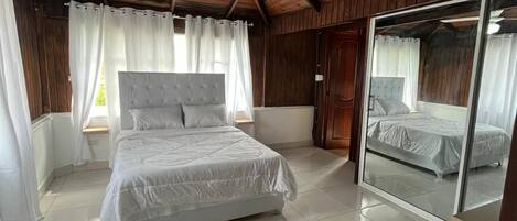 A bedroom with a large bed, a ceiling fan, and a sliding glass door.