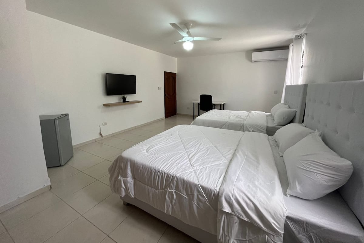 Une chambre d’hôtel avec deux lits, une télévision, un ventilateur de plafond et un appareil de climatisation.